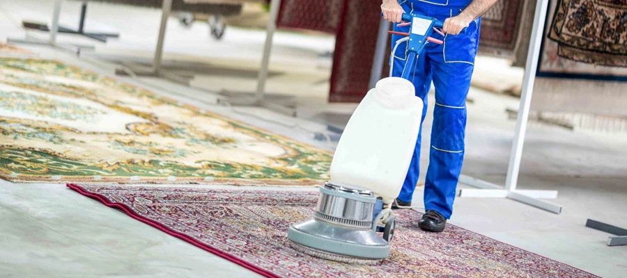 carpet cleaning guy wearing blue pants cleaning a rug with a large round vacuum