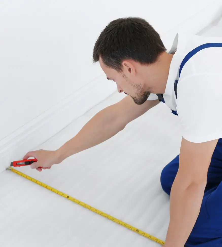 carpet repairman measuring and cutting a carpet to length.
