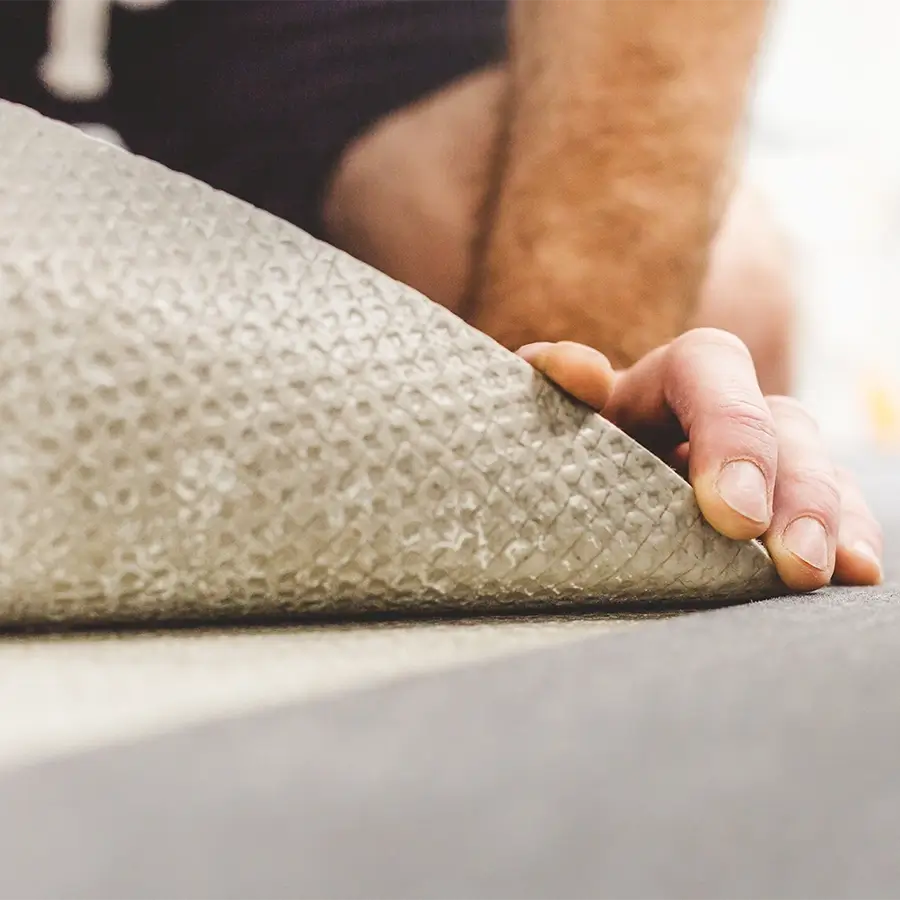 carpet repairman checking underneath the carpet for damages