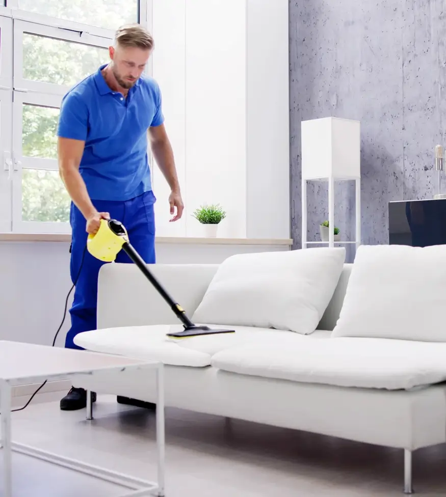 upholstery cleaning guy wearing blue shirt and pants vacuuming the couch